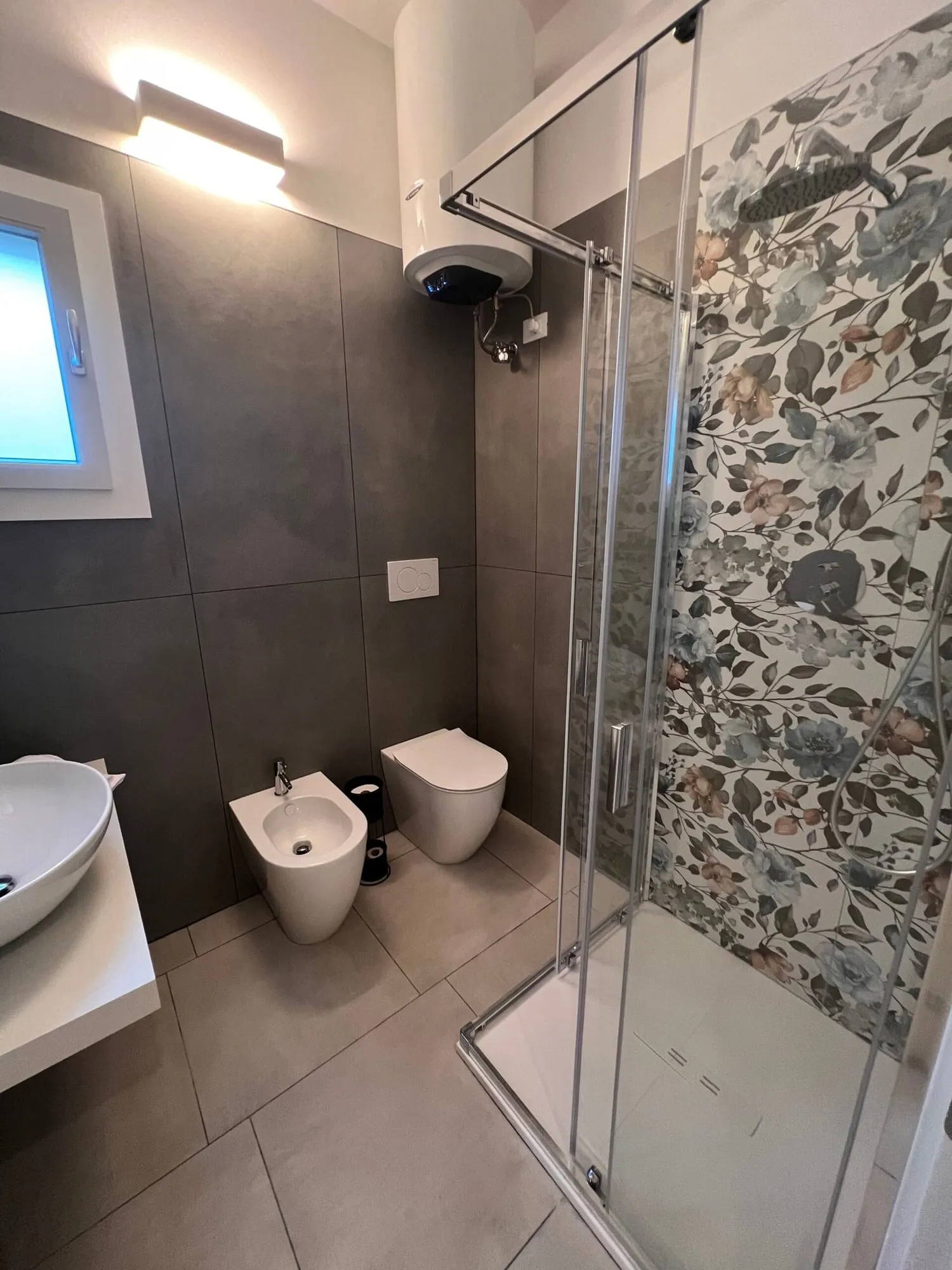 Bagno con doccia in vetro e piastrelle decorate